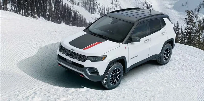 A white 2026 Jeep Compass driving through snow.